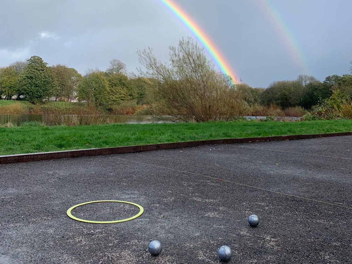 A rainbow over the River Taff, seen from the pistes, with boules and a throwing circle in the foreground
